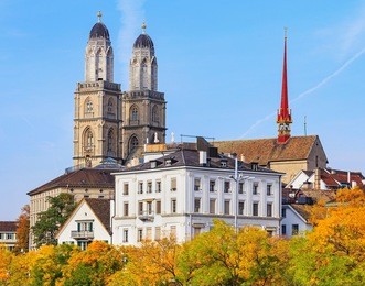 colorful trees and towers of the grossmunster cathedral in the city of zurich, switzerland. the picture was taken in the very end of september.