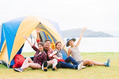 happy asian friends having a good time together while travel camping vacation trip by the lake