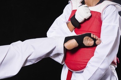 advertising, education concept - two young athletes are taekwondo fighters and taekwondo fight wrestling olympics on black background.