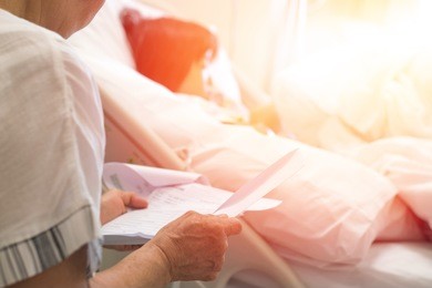 healthcare health insurance concept. parent looking at invoice or receipt paper document from hospital payment department expenses of ill kid patient 