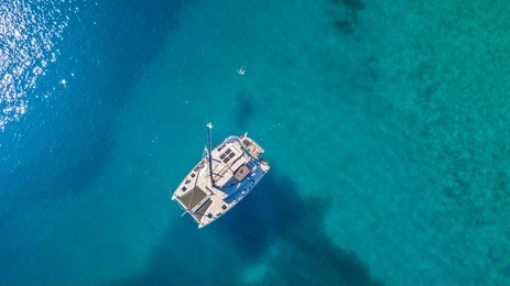 aerial view of catamaran anchoring on coral reef. bird eye view, water sport theme.