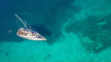 aerial view of sailing boat anchoring on coral reef. bird eye view, water sport theme.