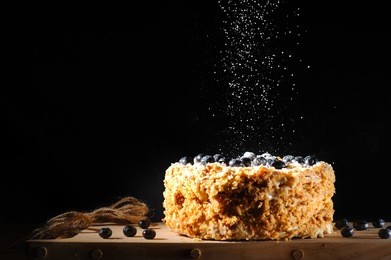 napalion cake, pie, layered cake, puff cake with blueberry sprinkled with powdered sugar, black background. twine