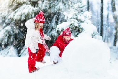 children build snowman. kids building snow man playing outdoors on sunny snowy winter day. outdoor family fun on christmas vacation. boy and girl play snow balls. winter clothing for baby and toddler.