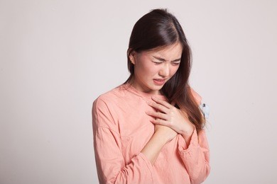 young asian woman got chest pain on gray background