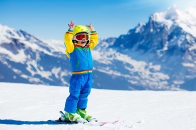 child skiing in mountains. active toddler kid with safety helmet, goggles and poles. ski race for young children. winter sport for family. kids ski lesson in alpine school. little skier racing in snow