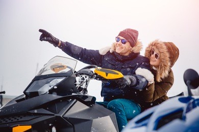 lovers. guy and girl on a snowmobile. concept winter vacation for family. shine of the sun.