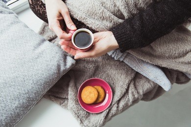 woman in warm clothes with tiny cup of black bitter coffee in hands. plate with cookies and girl with coffee cup. winter cozy atmosphere, breakfast concept