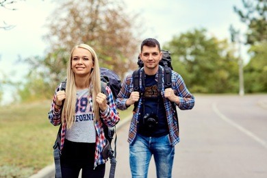 a young couple of tourists hikers in a hike on the road