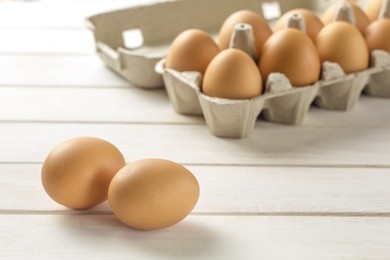 raw, brown, chicken eggs on wooden white boards.