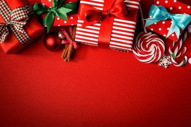 top view of red background with composed giftboxes and sweets for christmas holiday.