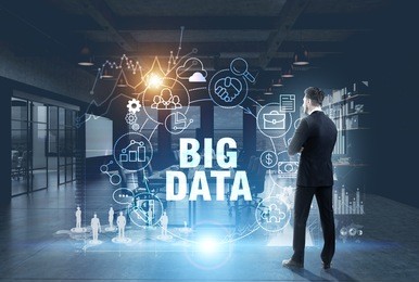 rear view of a bearded young businessman in a dark suit looking at a big data hologram in an office. toned image double exposure elements of this image furnished by nasa