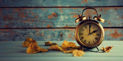 autumn time change, autumn leaves and alarm clock.