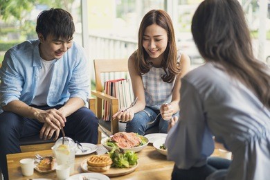 cheerful multiracial friend smiling and eating healthy food in a restaurant, group of happy friend concept