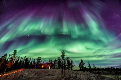 amazing aurora in purple and blue color dancing over chalet in yellowknife