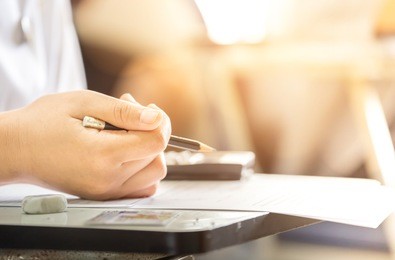 soft focus.high school or university student holding pencil writing on paper answer sheet.sitting on lecture chair taking final exam attending in examination room or classroom.student in uniform.