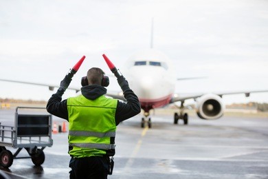 ground crew signaling to airplane on wet runway