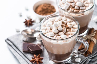 winter hot drink. hot chocolate or cocoa with marshmallow and spices on white background. view with copy space.