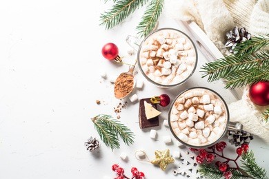 winter hot drink. christmas hot chocolate or cocoa with marshmallow on white with christmas decorations. top view with copy space.