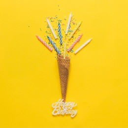 greetings for birthday with ice cream cone , candles and confetti. minimal flat lay. fashion concept