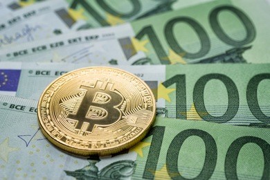 crypto currency concept - a bitcoin with euro bills