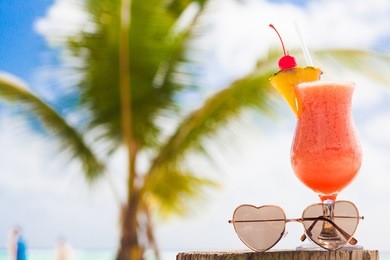 glass of fruit cocktail and sunglasses by the beach