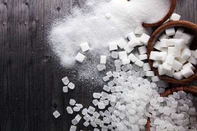 bowl with white sand, crystal and lump sugar on wooden background.