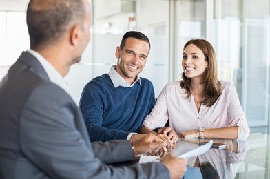 mature financial advisor showing report to young couple for their investment. salesman and positive couple talking about purchase. happy couple consulting financial agent for loan.