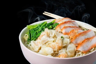egg noodle and wonton in hot soup with red roast pork isolated in black background