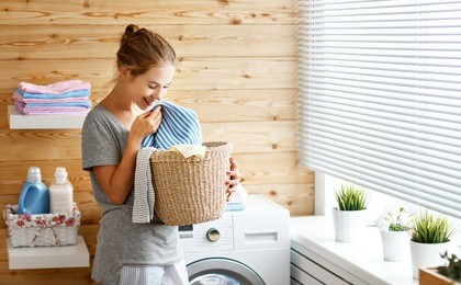 a happy housewife woman in laundry room with washing machine  
