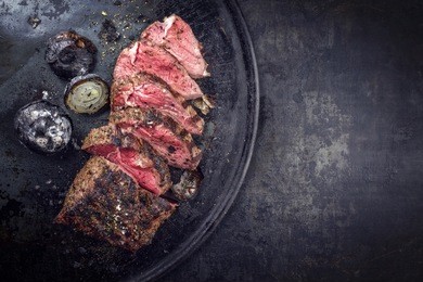 barbecue dry aged caveman wagyu chateaubriand steak with onions sliced as close-up on a board 
