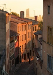 a woman walking in an alley in vieux lyon, the old town of lyon that is part of the unesco world heritage site, during sunrise. lyon, france.