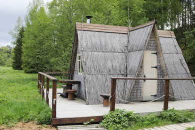 wooden triangle house in green forest in overcast summer day