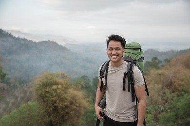 happy asian hiker. man with backpack hiking in beautiful forest