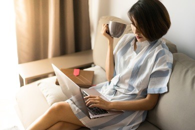 asian woman relax after sending her job with a cup of drink in her bed .  concept for digital nomad, internet of thing, independent location
