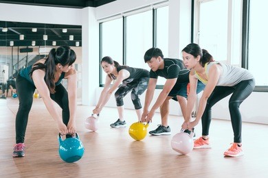 expert instructor starts to educate a team of fitness learner exercise with kettle bell in the classroom.