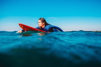 surf girl floats on surfboard. woman in ocean during surfing. surfer and ocean