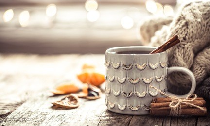 details of still life in the home interior living room. beautiful cup of tea with tangerines and sweaters on wooden background . cosy autumn-winter concept
