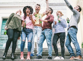 happy crazy friends celebrating on the street drinking beer and throwing confetti - young students having fun together - friendship and youth concept - vsco warm filter - main focus on center guys