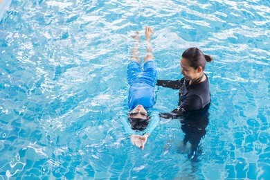 girl learning to swim with coach at the leisure center