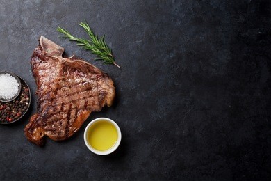 grilled t-bone steak on stone table. top view with copy space