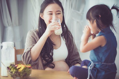 happy asian family mom and daughter drink milk at home .