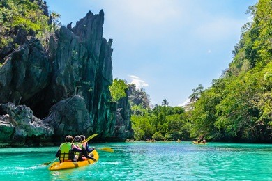 kayaks in the big lagoon with turquoise clean water, tropical forest , rocks,,  el nido, palawan, philippines