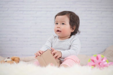 sweet beautiful baby girl wrapping ribbon on beautiful white furry.newborn baby concept. happy new year.