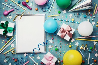 party or birthday background. silver frame with colorful balloon, gift box, carnival cap, confetti, candy and streamer on vintage blue table top view. flat lay style. holiday or festive mockup.