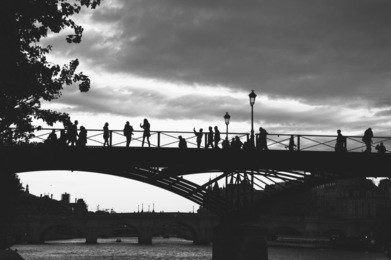 paris. silhouettes of  people on the bridge at sunset. conciergerie at background. black and white photo.