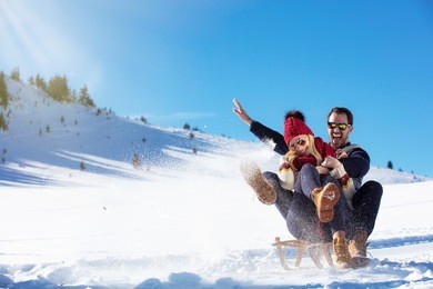 young couple sledding and enjoying on sunny winter day