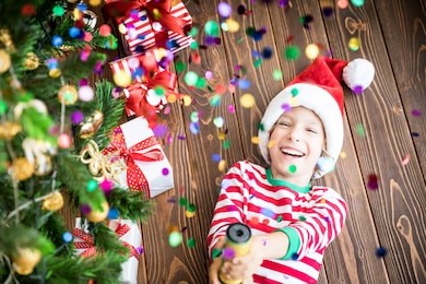 happy child holding party popper. funny kid on christmas eve. xmas holiday concept