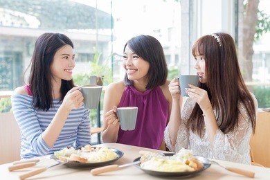happy woman friends sitting and chatting in restaurant