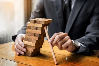 planning, risk and wealth strategy in business concept, businessman and insurance gambling placing wooden block on a tower.